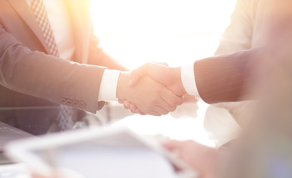 Two mean wearing suits shaking hands