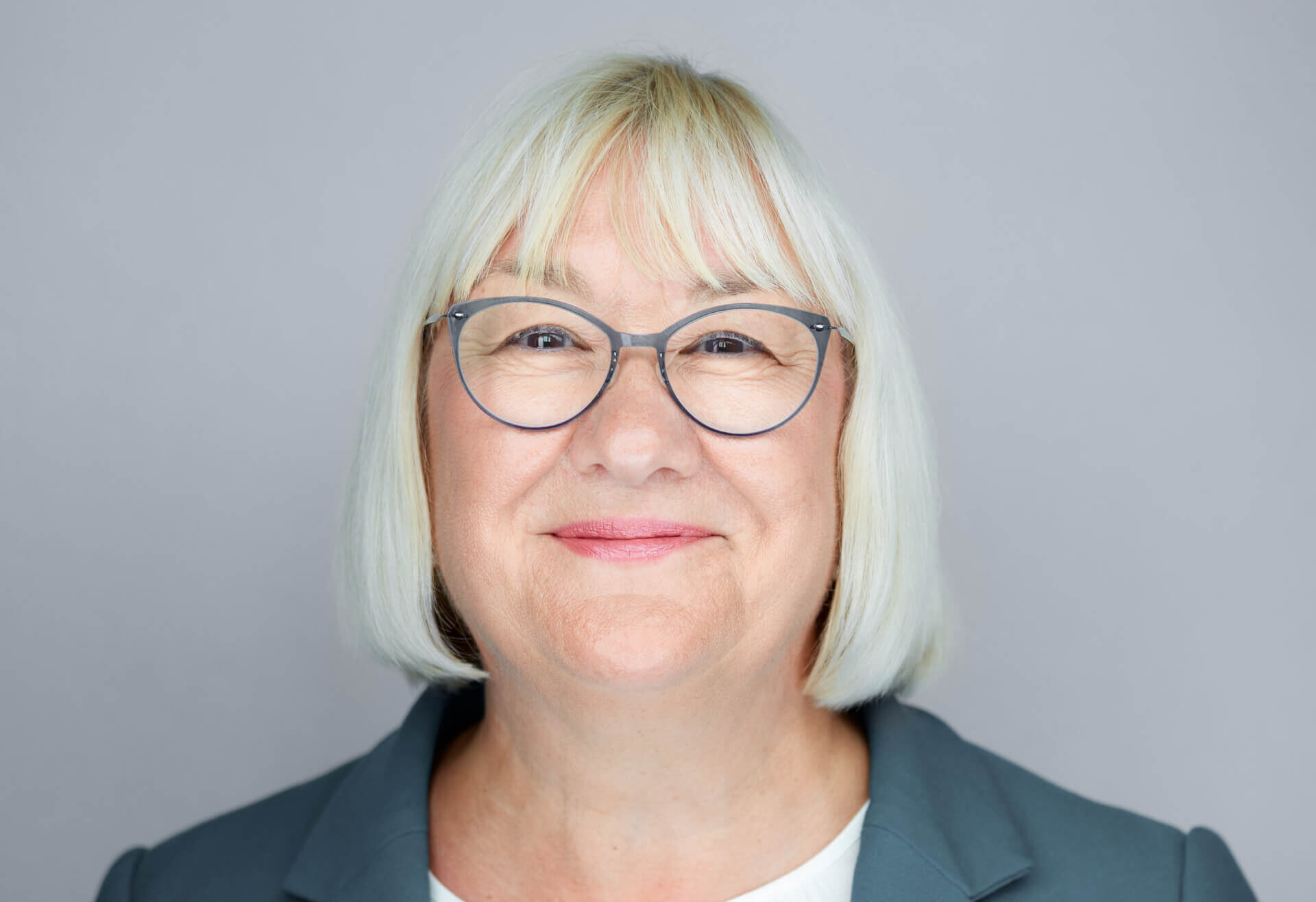 A smiling woman with bobbed hair wearing glasses