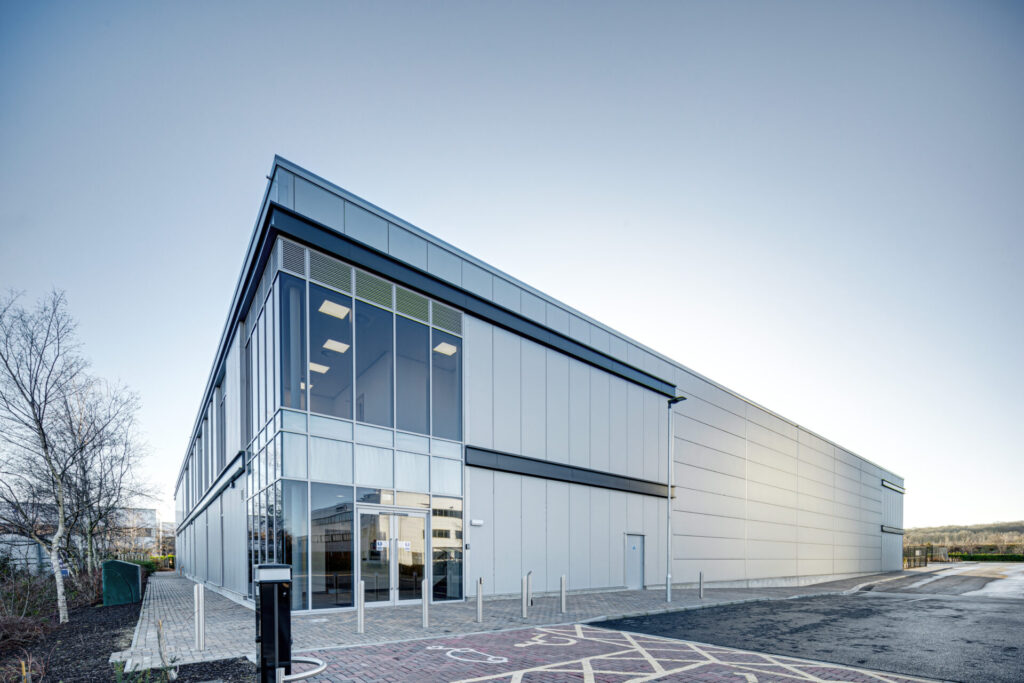 A modern low-rise warehouse building with a silver facade
