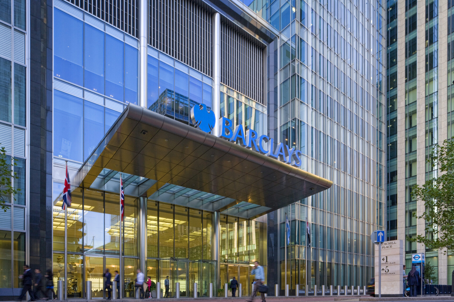 The entrance to Barclays' office headquarters at Canary Wharf with a large blue company logo above the entrance