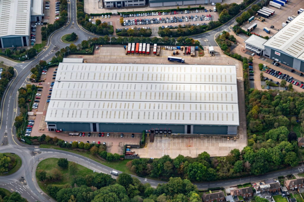 Aerial view of an industrial building surrounding by yard space and car parking
