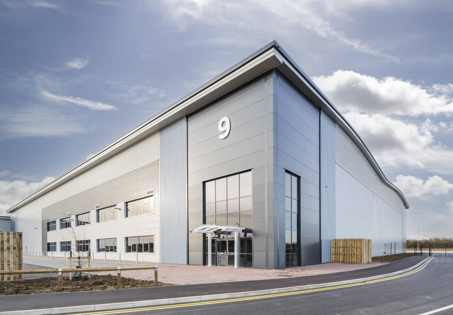 A modern steel clad warehouse featuring a series of windows on the corner and down the side