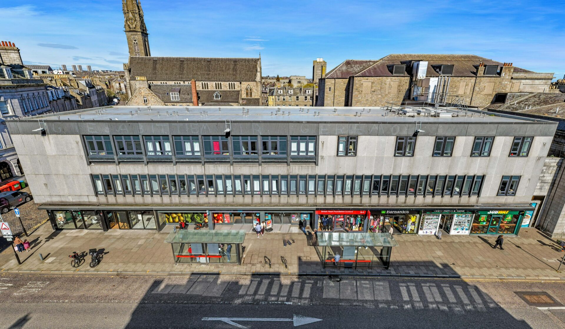 A low rise retail parade in Aberdeen city centre with shops along the bottom of the building and rows of windows above