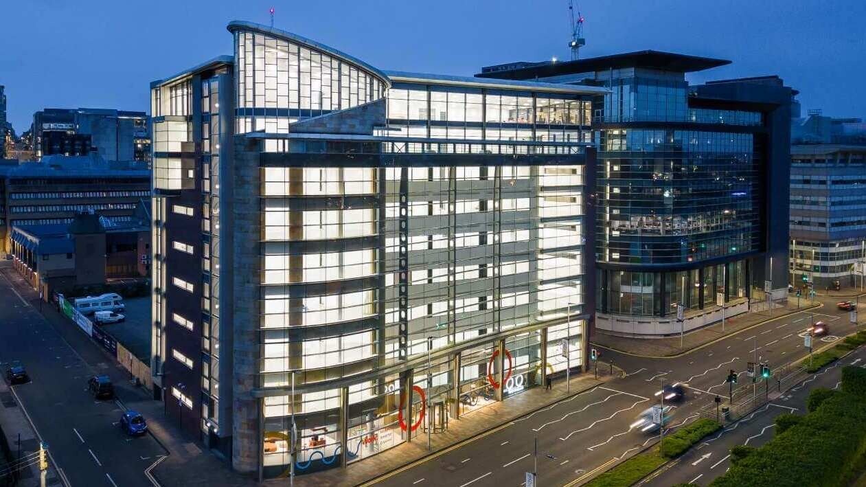A multi-storey office building in Glasgow city centre with a modern facade, fully lit up at night