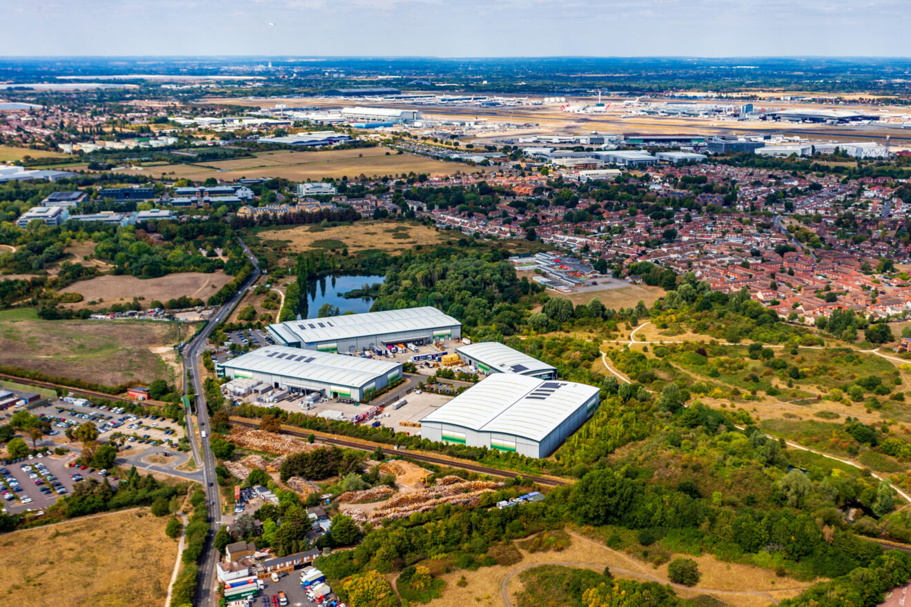 Four modern logistics units located on a site surrounded by grassland with Heathrow Airport in the distance