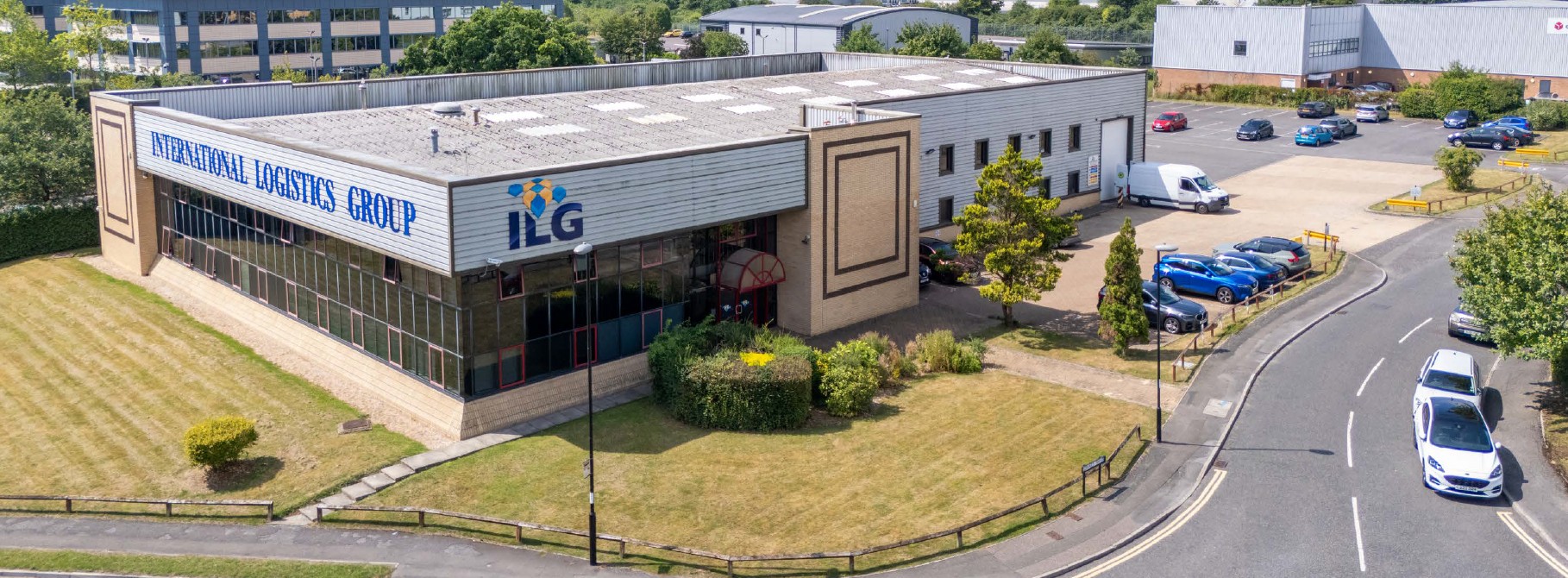 An old industrial building with car parking and green space to the front and side
