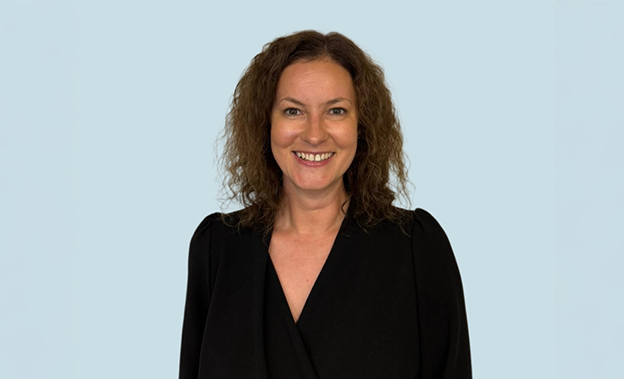 A smiling Rebecca Napier has brown curly hair and is wearing a black shirt