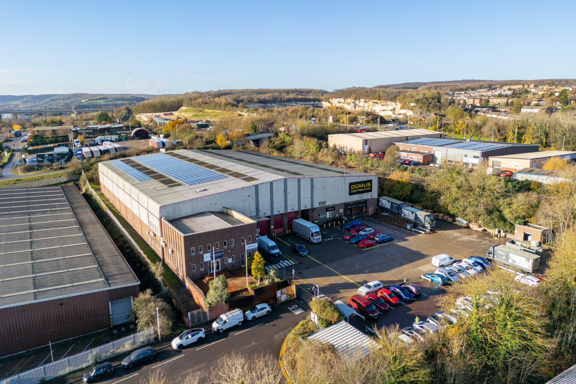 Aerial view of an industrial building with cars and vans parked in front