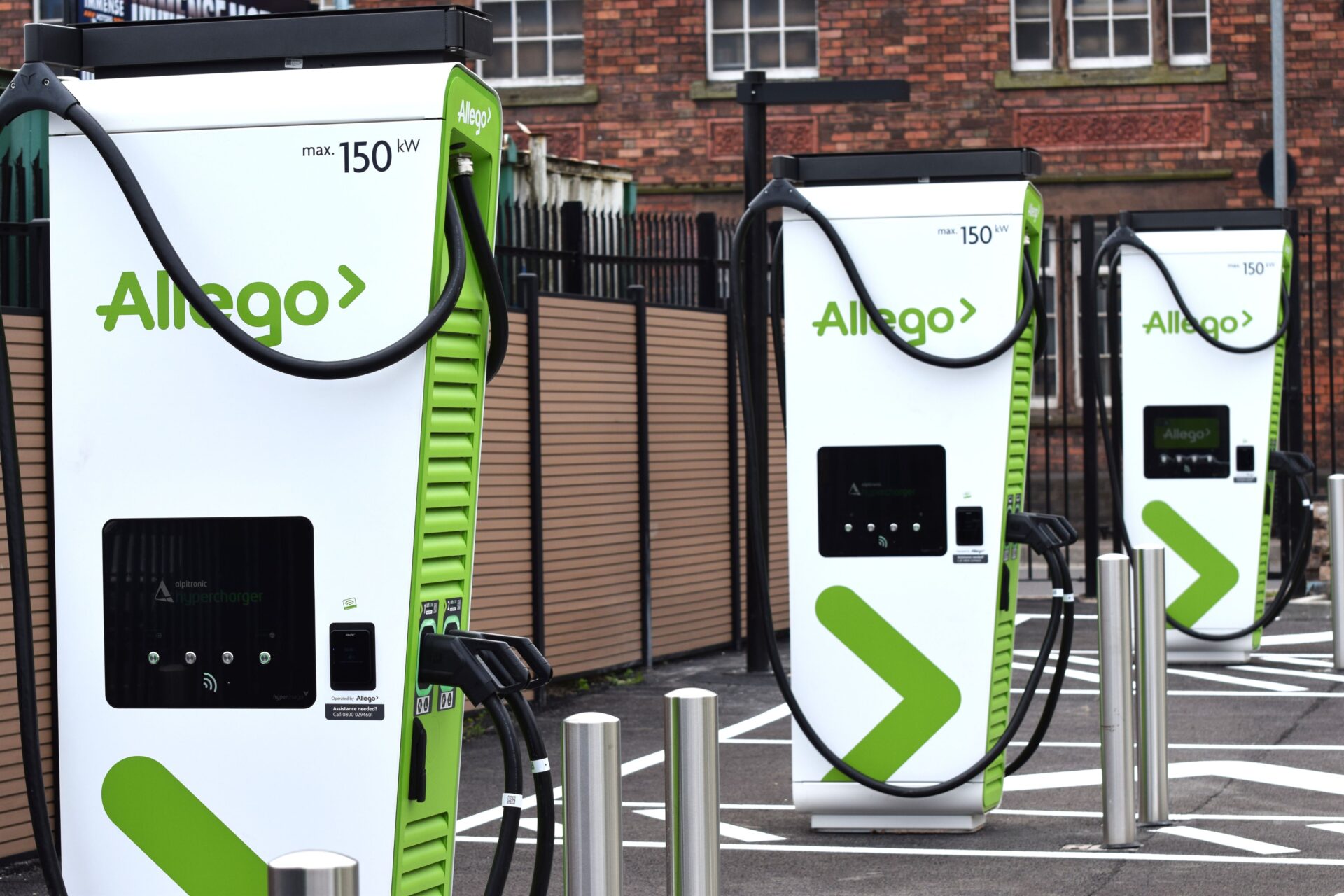 A row of three green and white EV chargers featuring the Allego logo