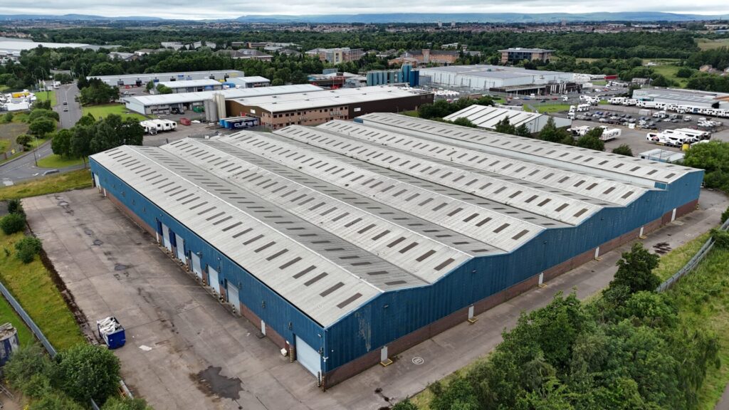 Aerial view of a large industrial building featuring peak roofs and blue walls