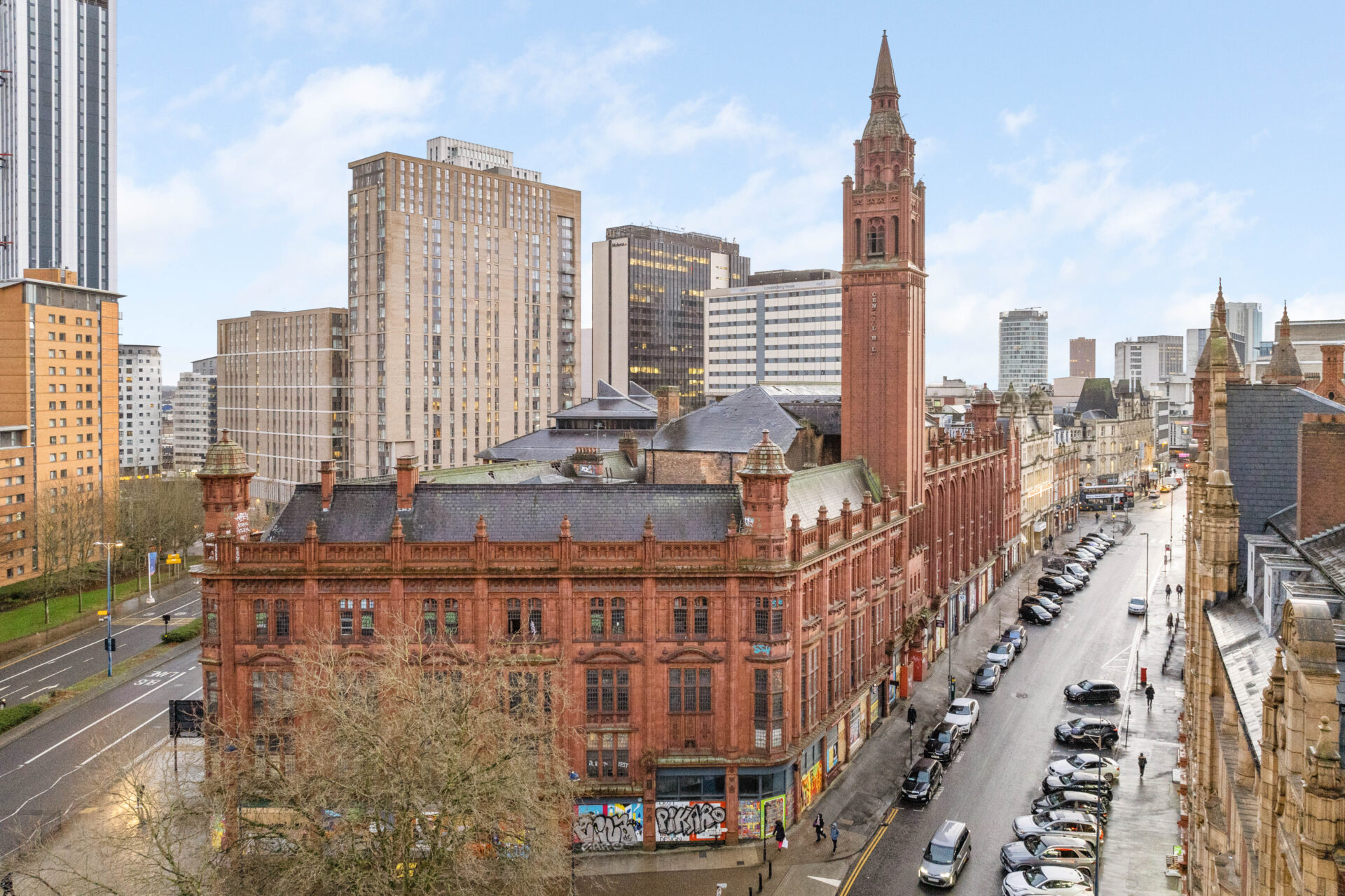 Street scene with an historic red brick built building in the foreground and larger buildings to the rear