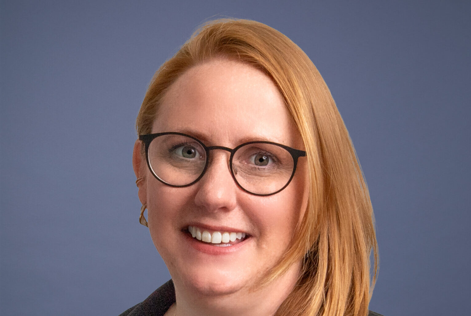 A smiling woman with long hair wearing glasses