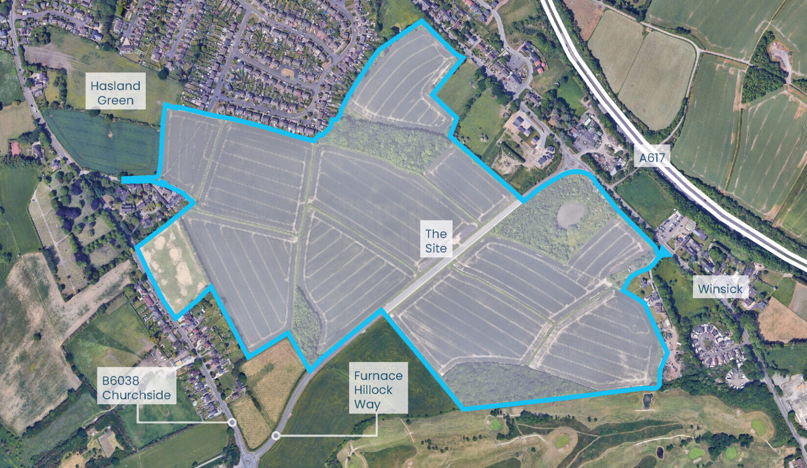 Aerial view of development land highlighted with a blue outline surrounded by houses and fields