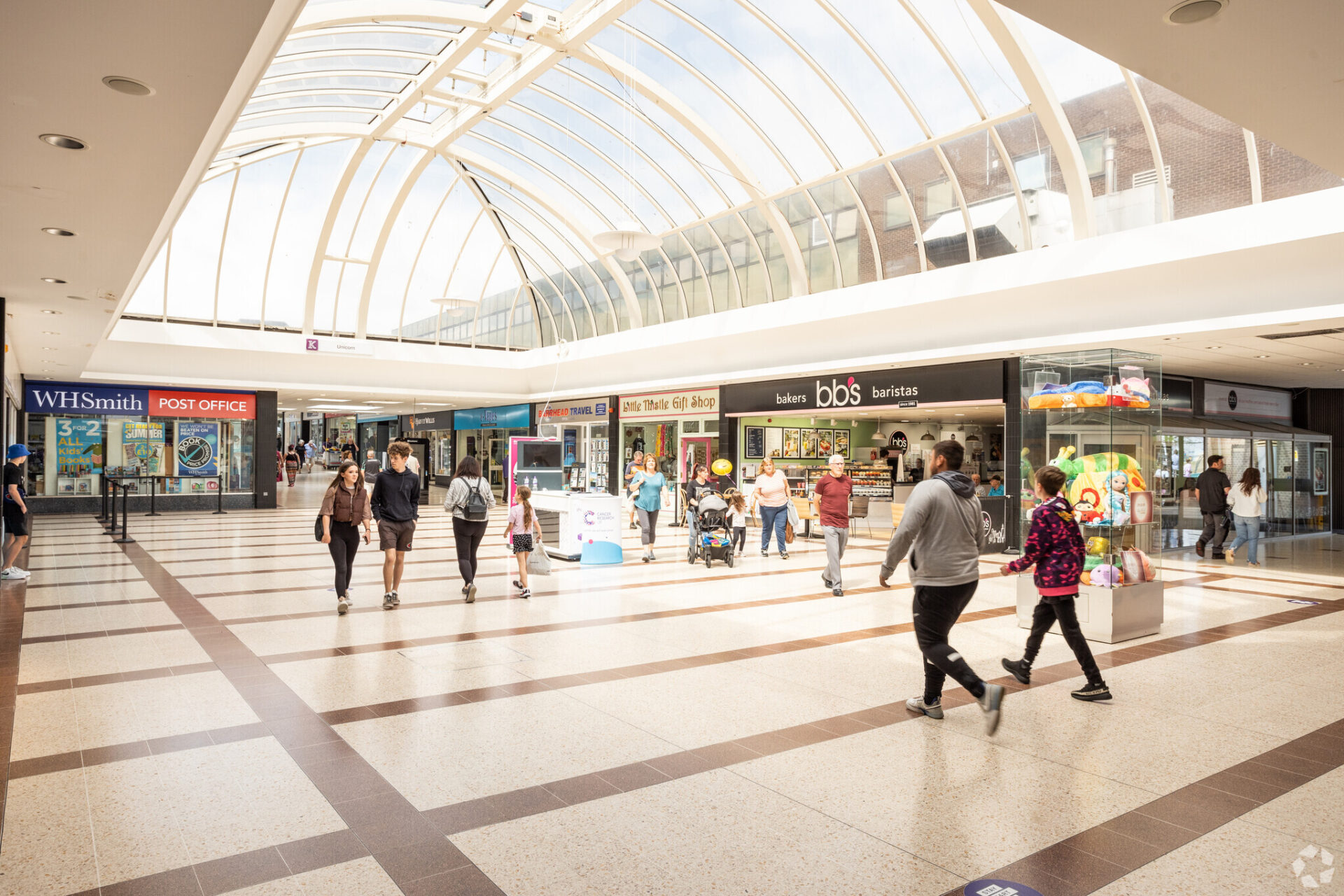 Interior of a shopping centre featuring lots of retail stores and shoppers