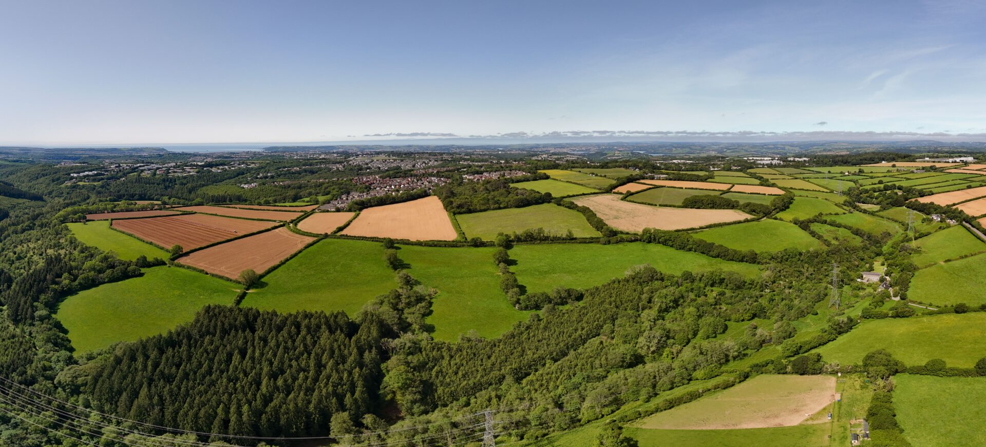 Aerial view of a patchwork of green fields with wooded areas