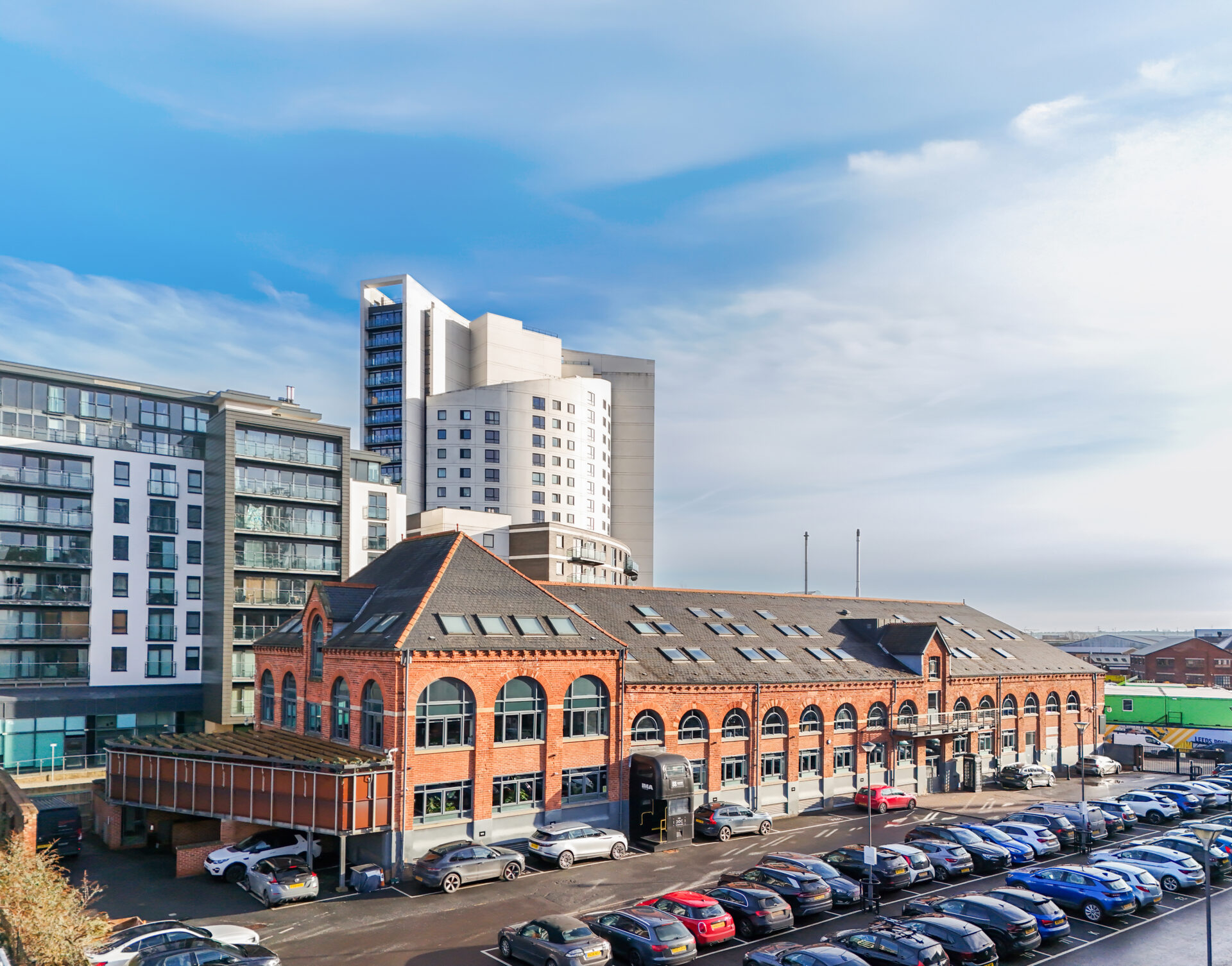 The Malthouse in Leeds is a red brick former brewery building with car parking to the front and large buildings to the rear