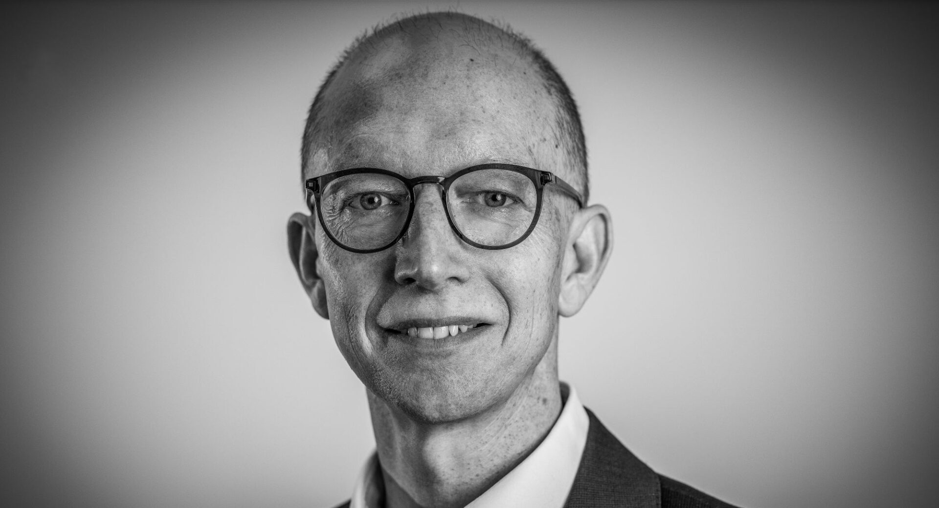 Black and white head and shoulders picture of a man wearing a suit