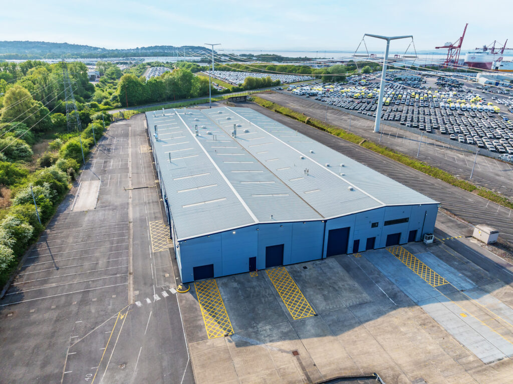 Aerial view of a large industrial building with lots of cars in the background