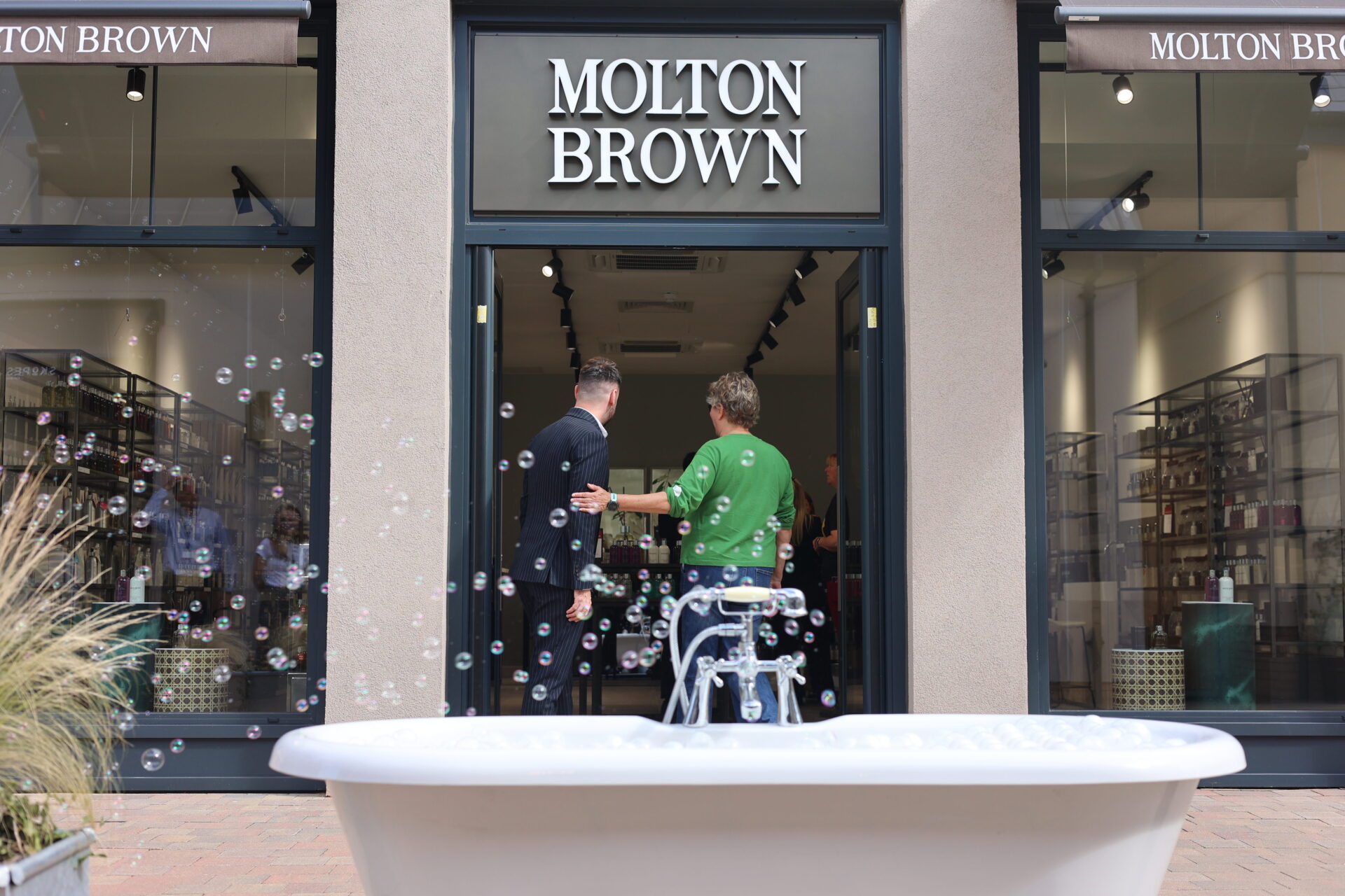 A roll top bath with bubbles rising above it in front of a Molton Brown retail unit