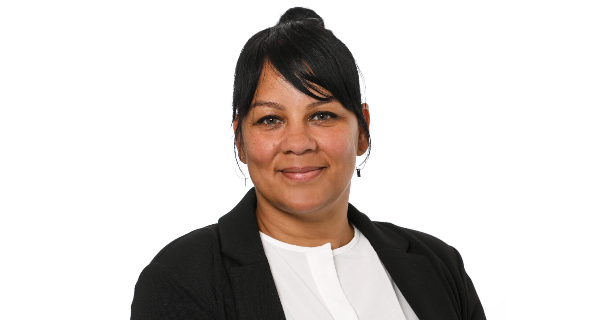 A smiling woman with black hair wearing a dark jacket and a white shirt