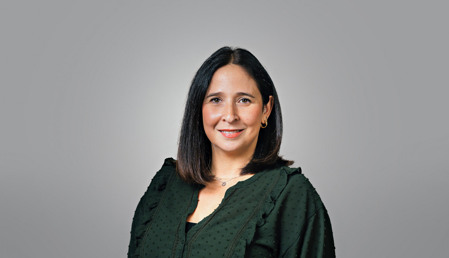 A smiling woman with shoulder-length dark hair wearing a dark green shirt