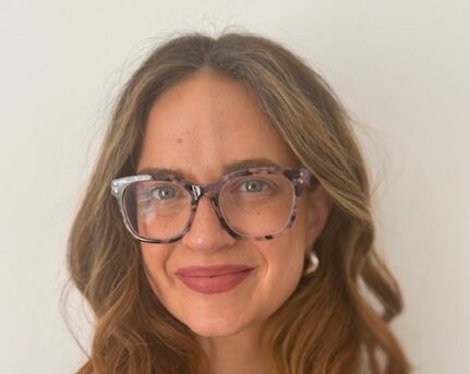 A woman with long brown hair wearing glasses