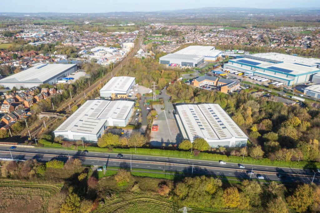 Aerial view of a series of industrial buildings at Stone Cross Park surrounding by trees and greenery