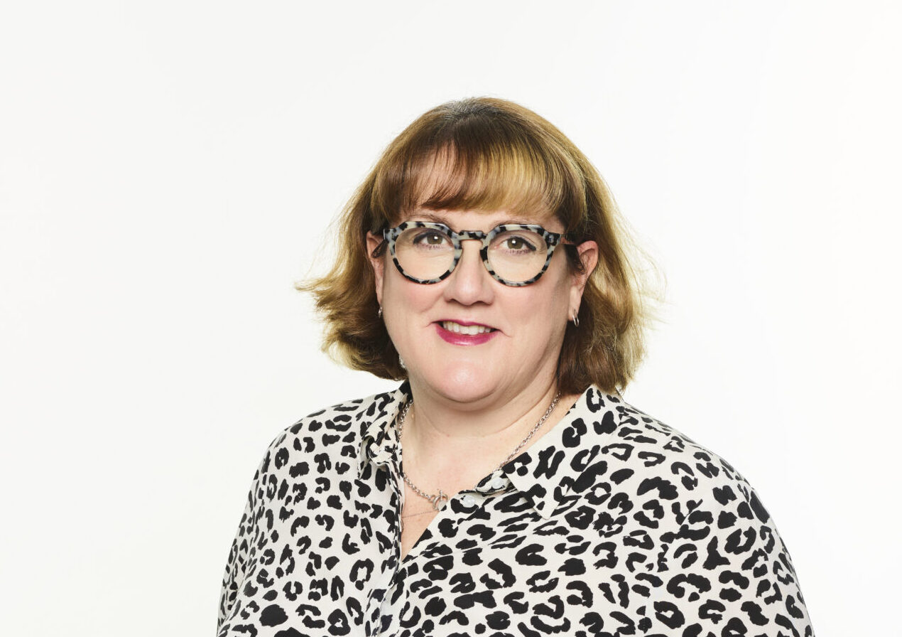 A woman with a brown bob hair cut wearing glasses and a patterned shirt
