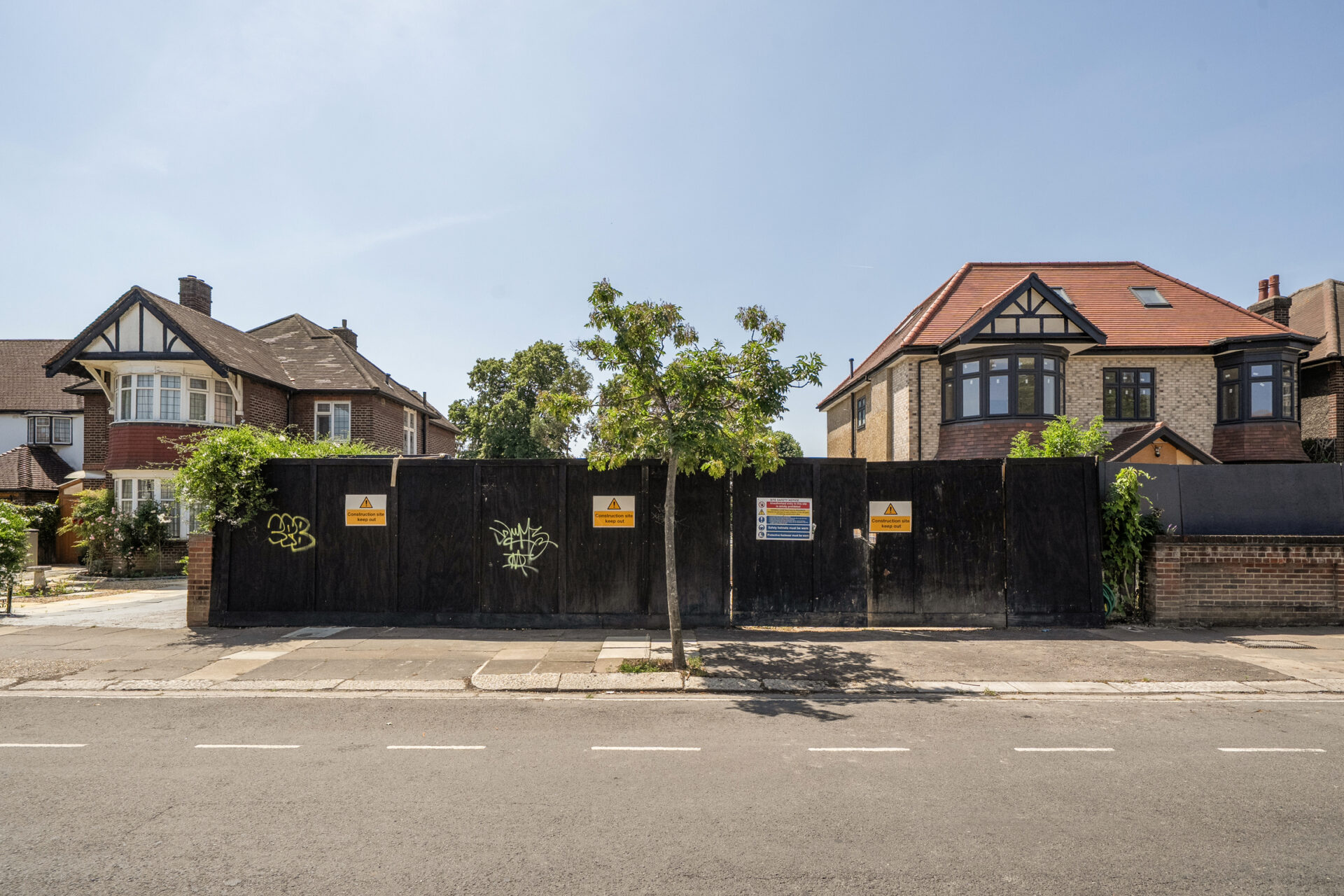 Hoardings between two residential buildings with a main road running in front