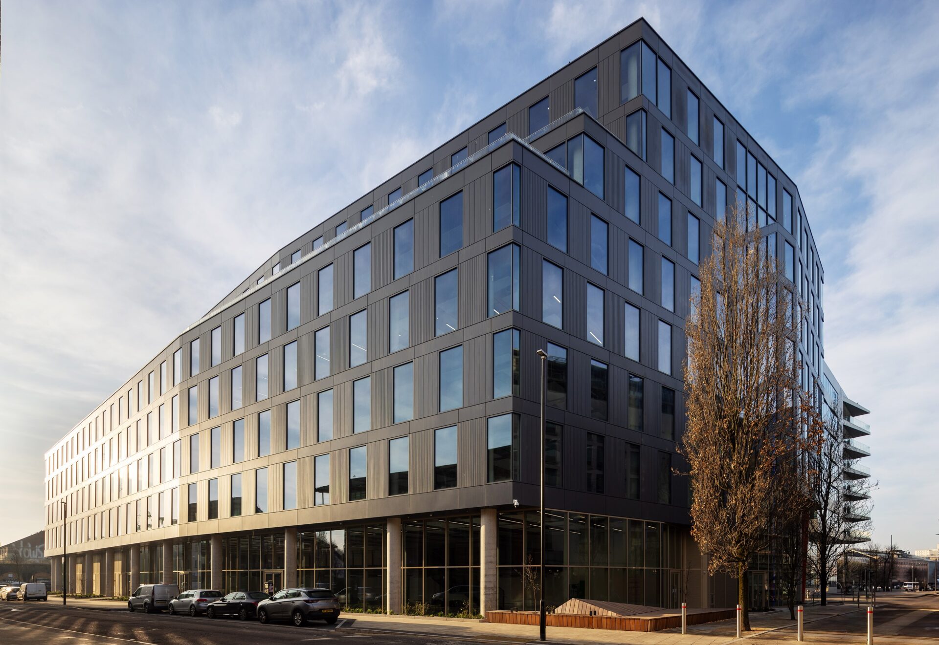 A striking, dark coloured modern office building with lots of windows to the side and front