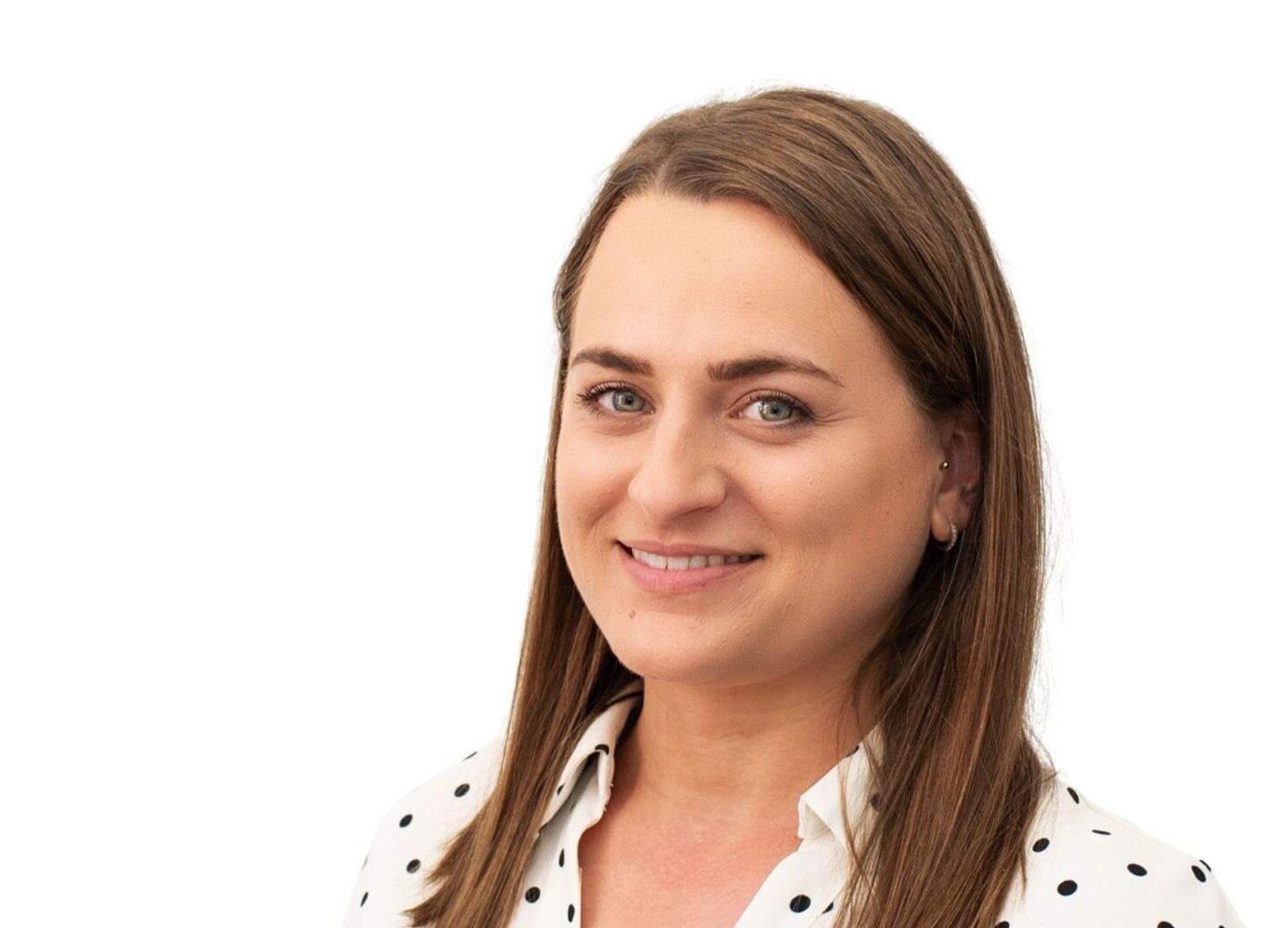 A female with long brown hair wearing a white polka dot shirt