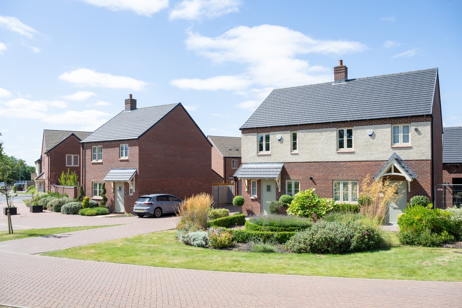 A row of modern new build houses with gardens and car parking to the front