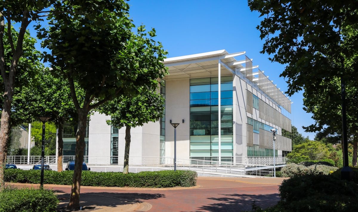 A modern white building surrounded by trees and greenery