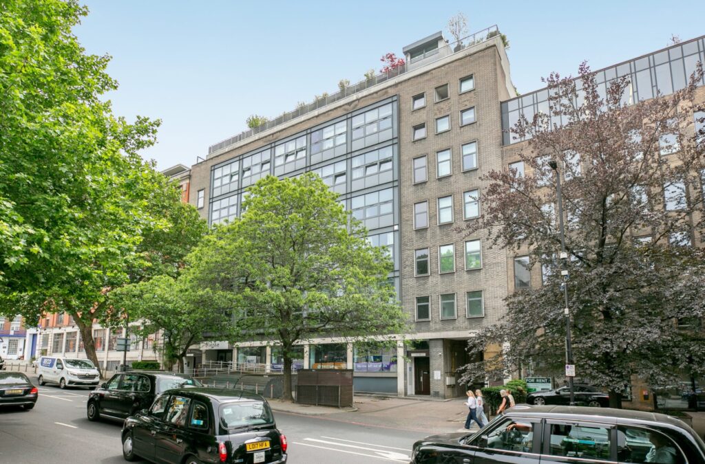 Exterior view of an office building with a tree-lined main road in front