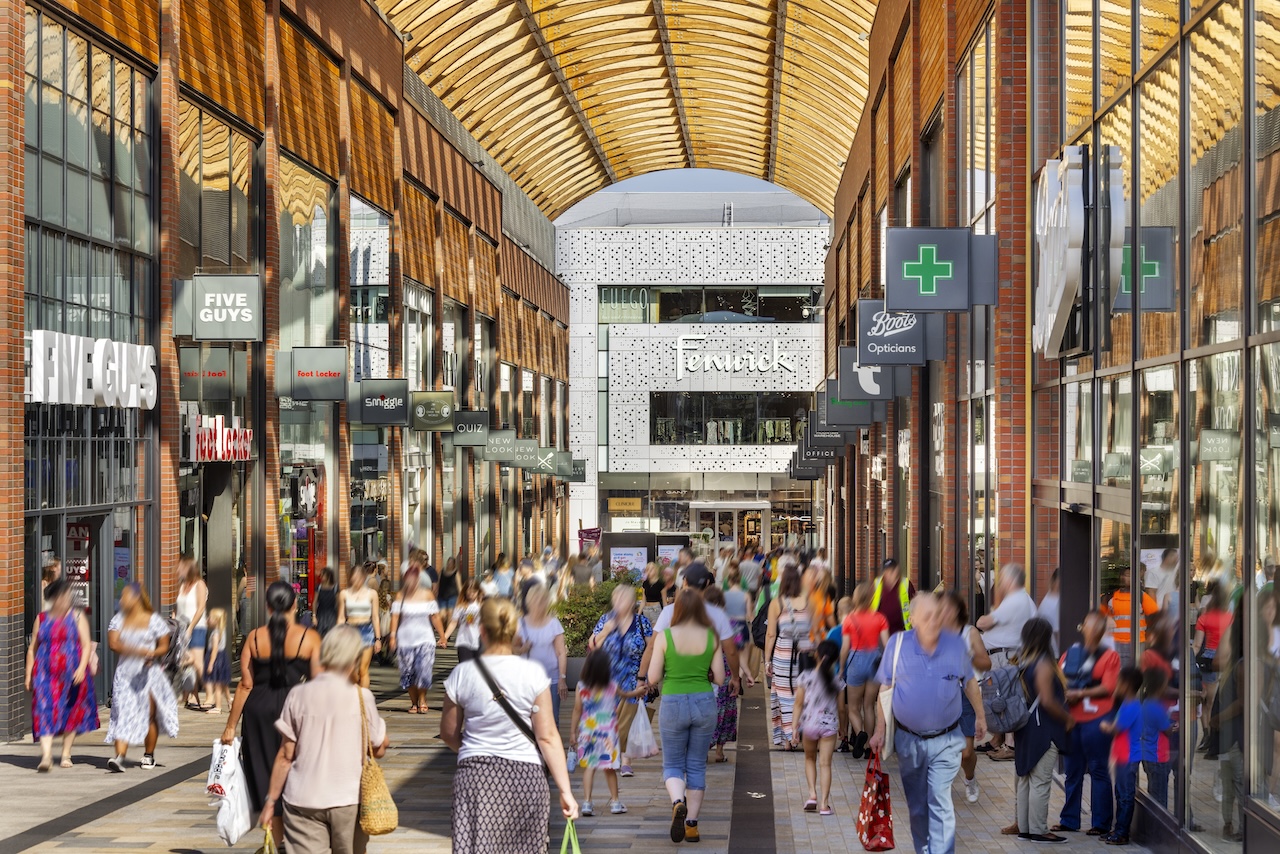 Shoppers walking down an arched street with retail stores on either side and a Fenwick store at the end of the street