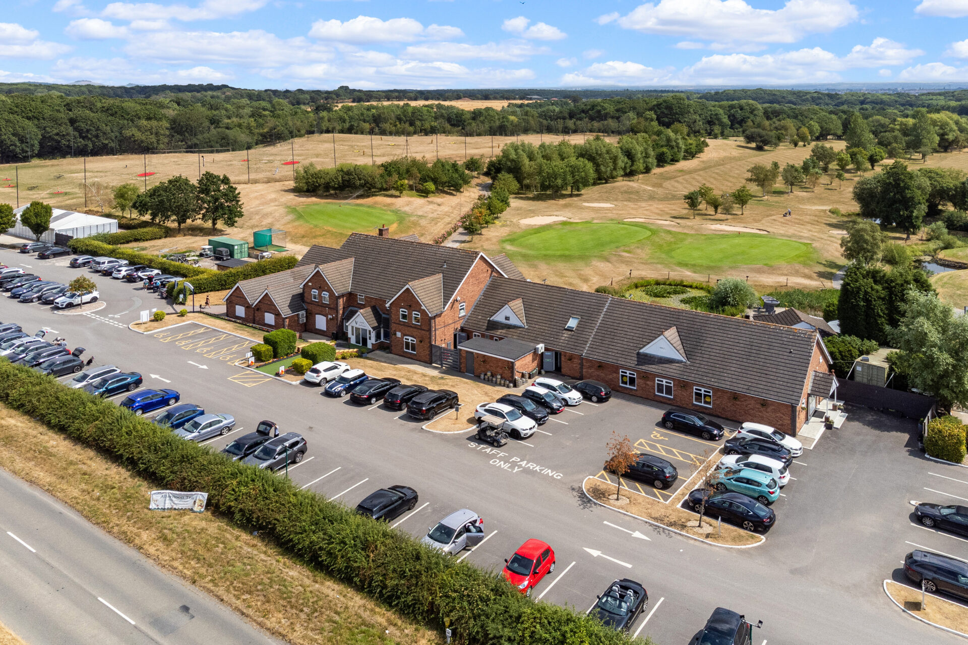 Aerial view of a golf course featuring a club house and car parking to the front