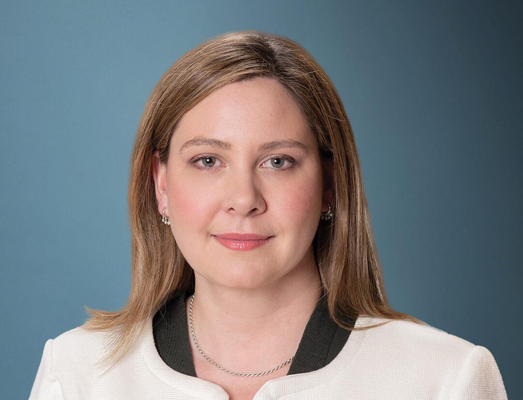 A woman with long brown hair wearing a white jacket