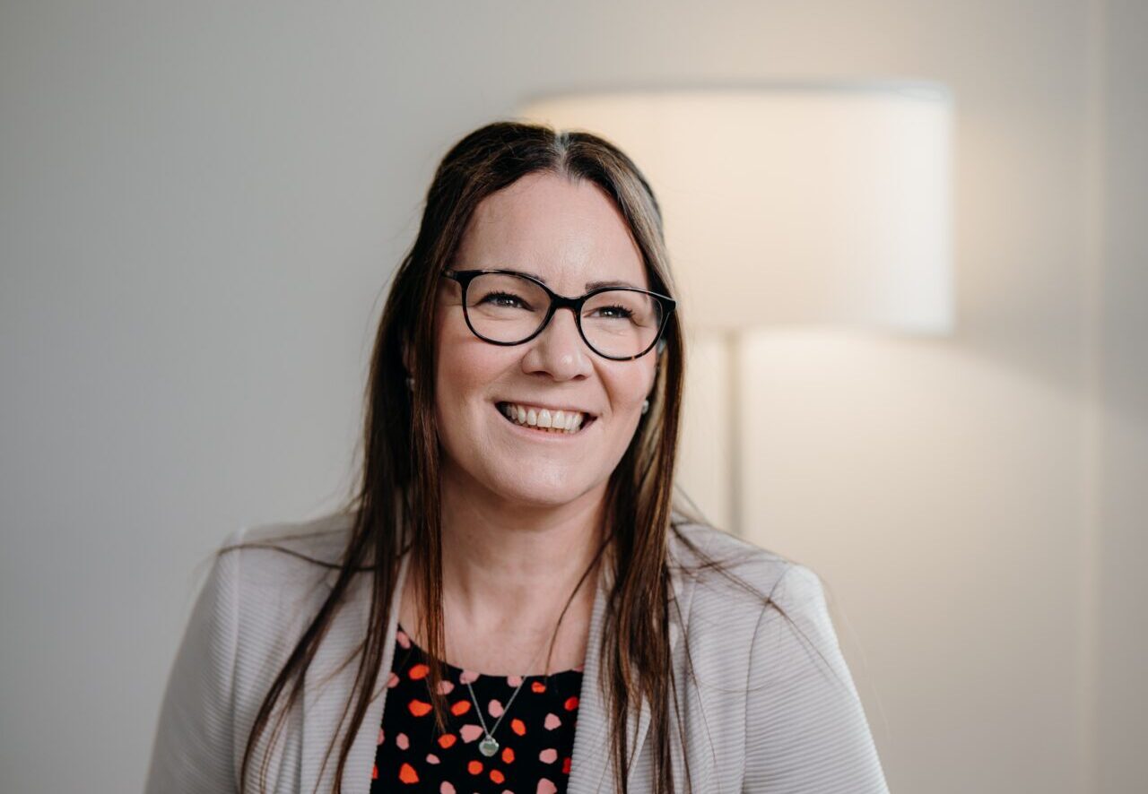 A smiling woman wearing glasses with long hair