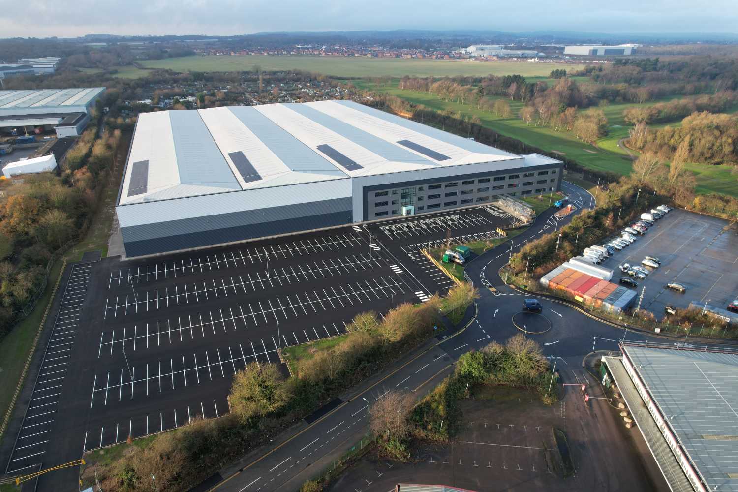Aerial view of a modern logistics unit with lots of car parking in front and to the side