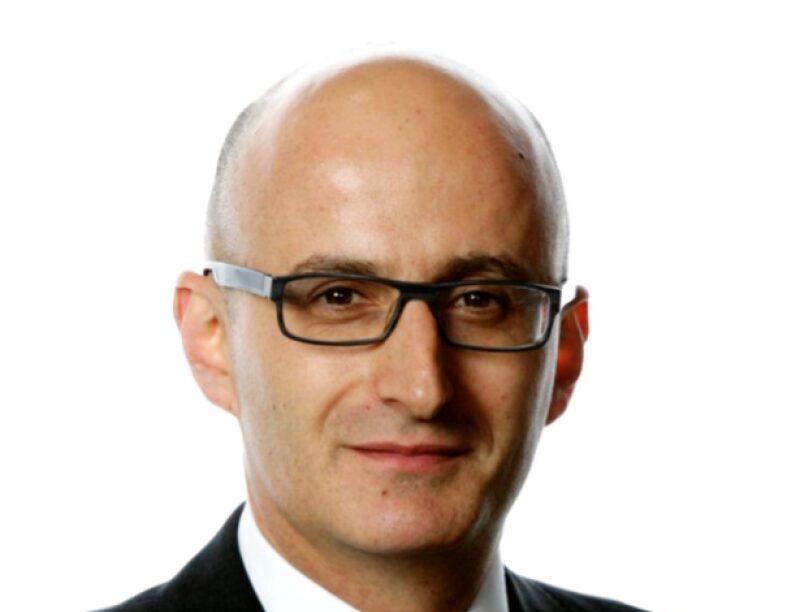 A bald man wearing black rimmed glasses