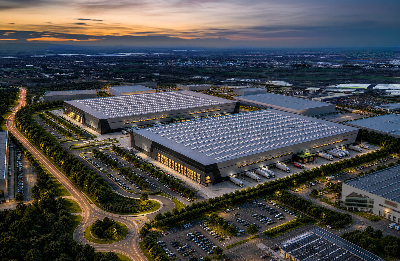 CGI image of two large lit up industrial buildings at dusk