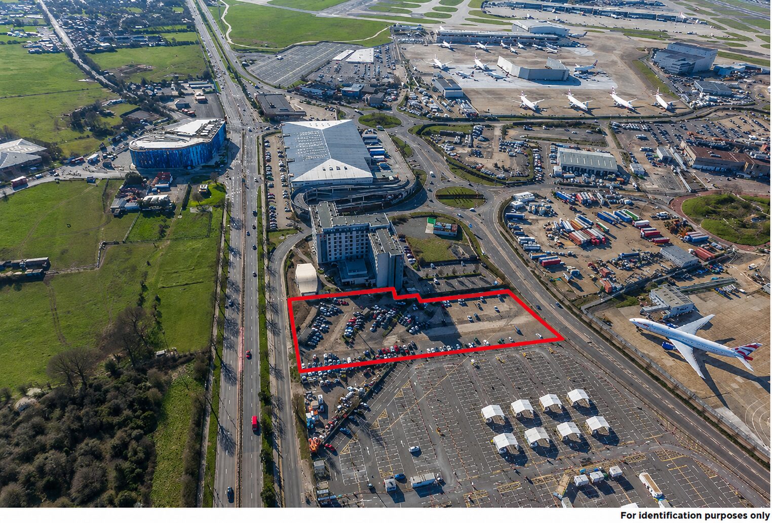Aerial view of an industrial site marked in red with an airport in the background