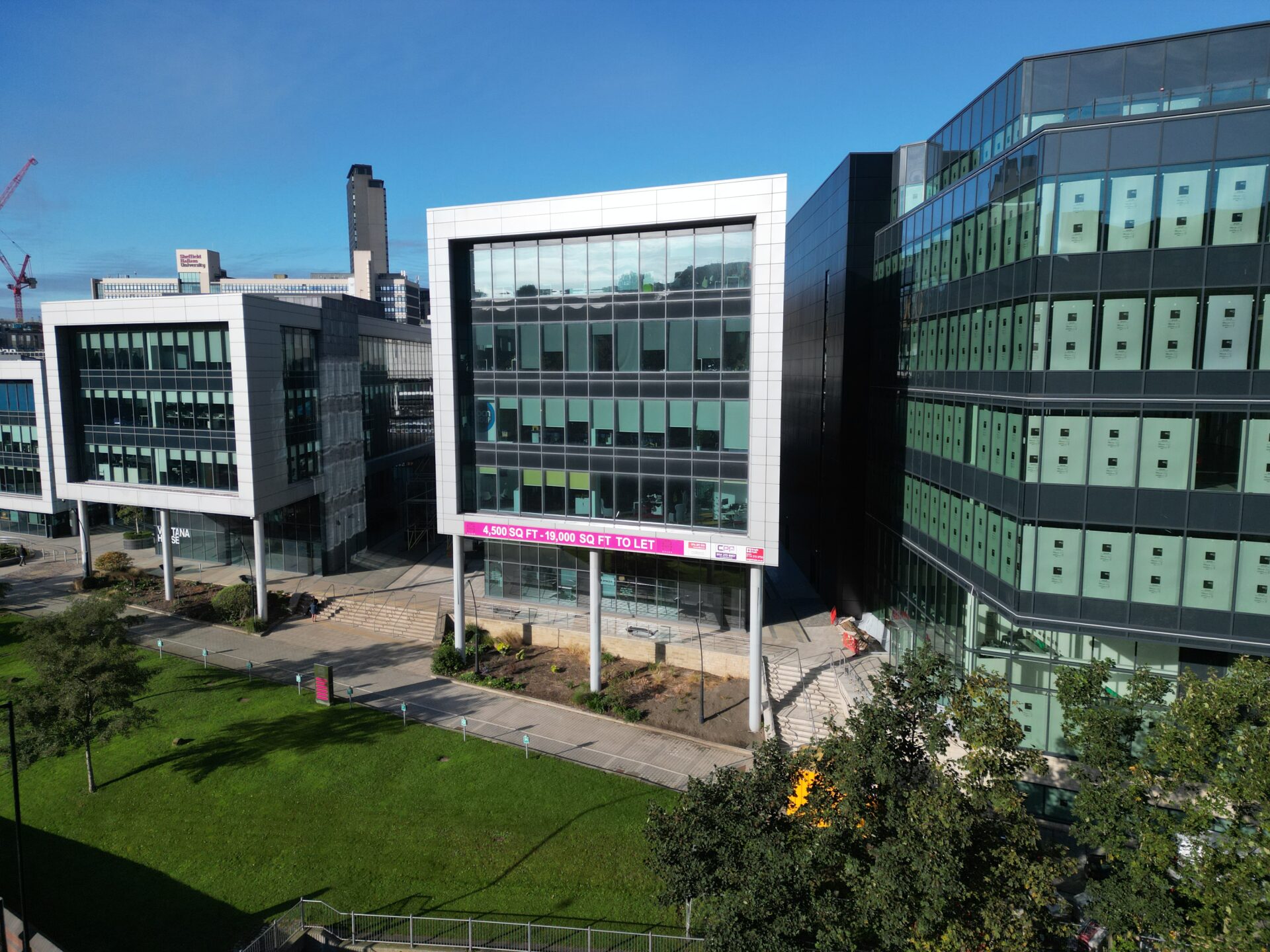 A modern looking glass fronted office building with green space in front