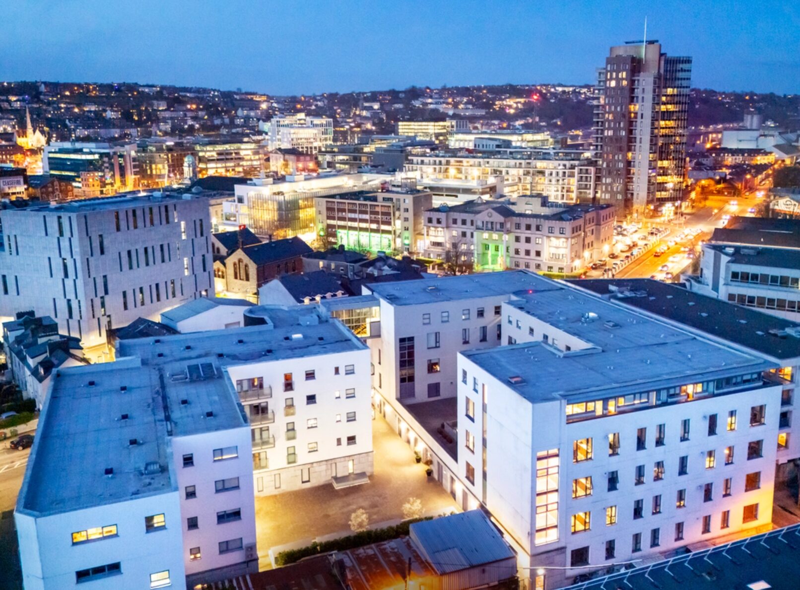 Aerial view of a city at dusk featuring lots of different sized buildings
