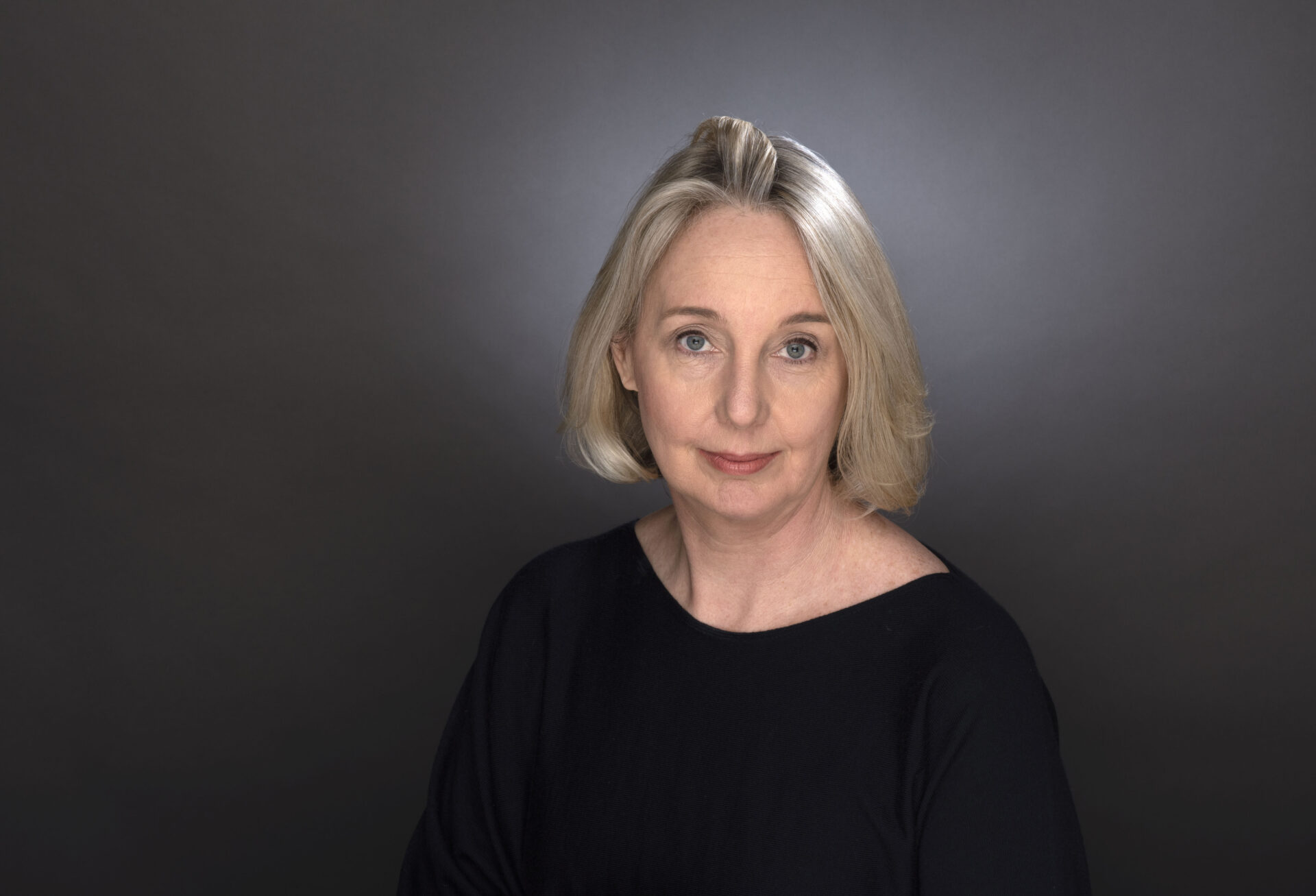 A woman with a blonde bob wearing a dark shirt