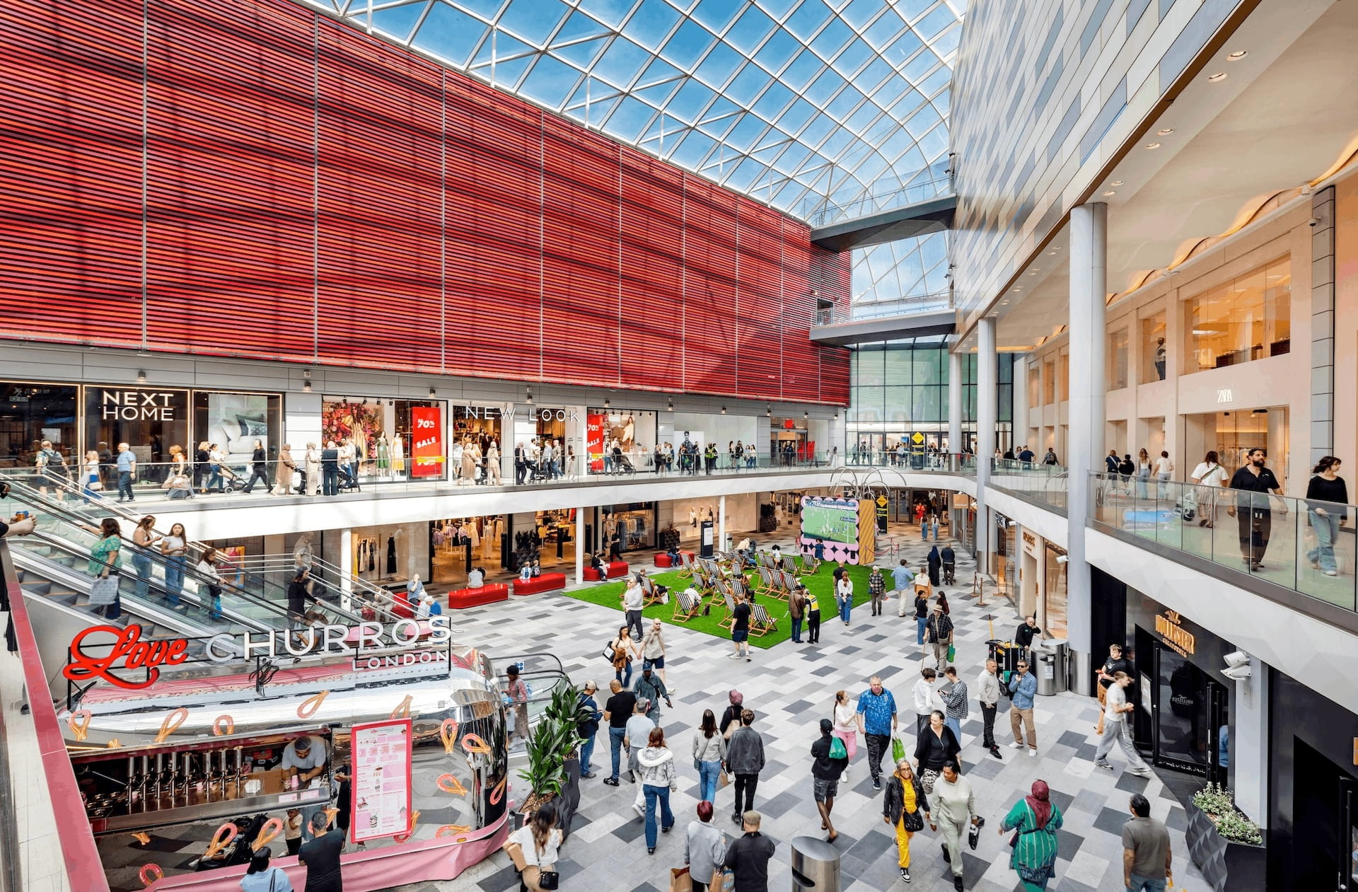 Interior of a shopping centre featuring lots of shops and shoppers