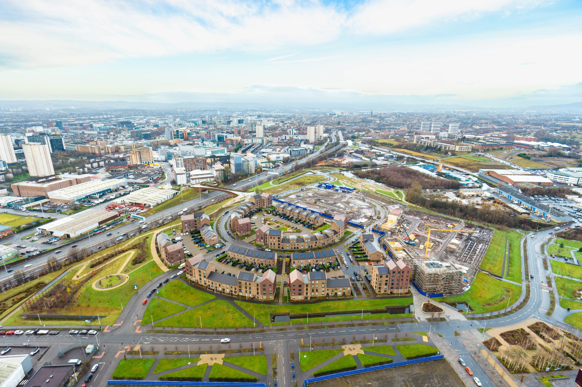 Aerial view of a residential development surrounded by a road network with a large city in the background