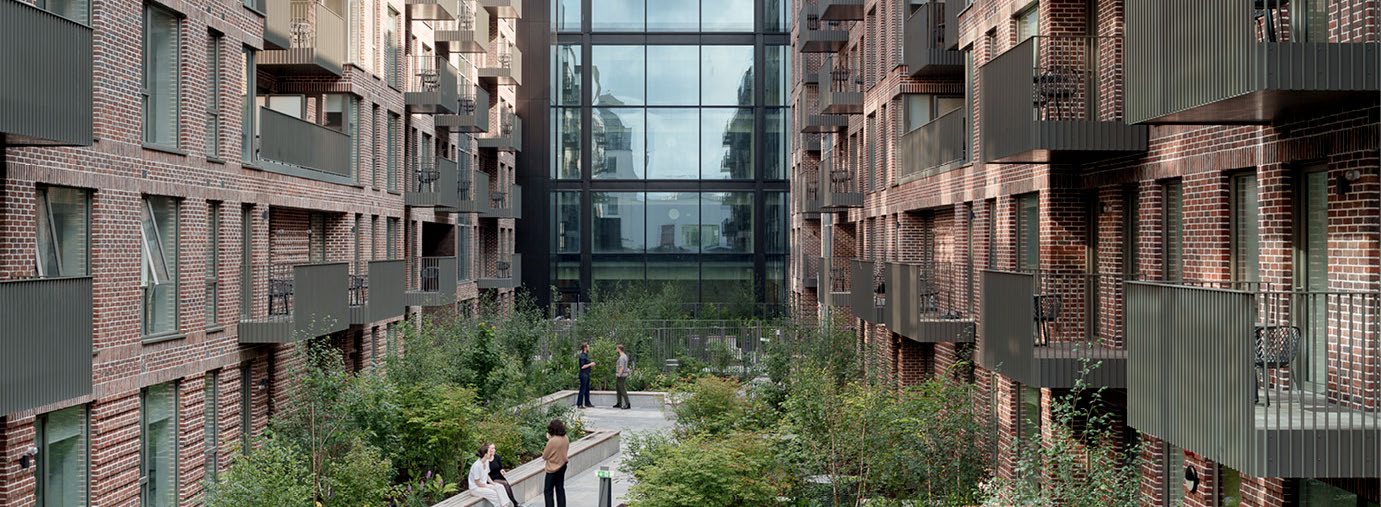 A courtyard filled with plants with brick buildings