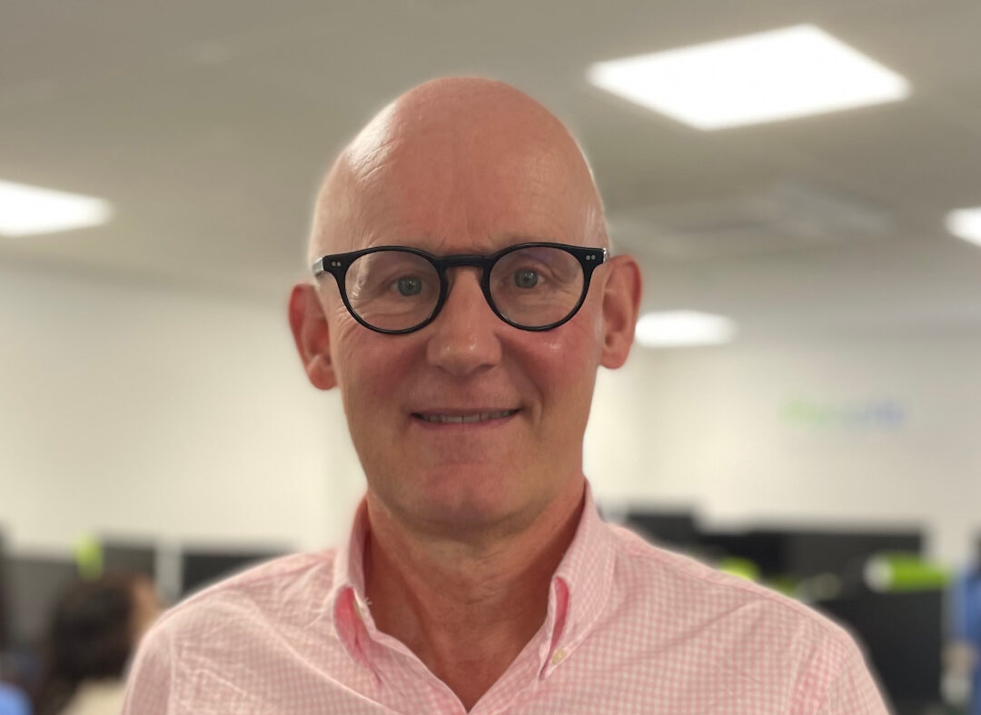 A bald man wearing glasses and a pink shirt