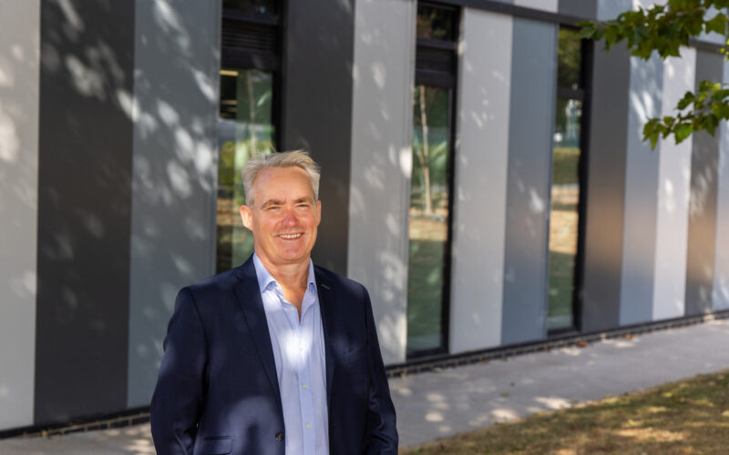 A man wearing a dark suit jacket stood infront of a building